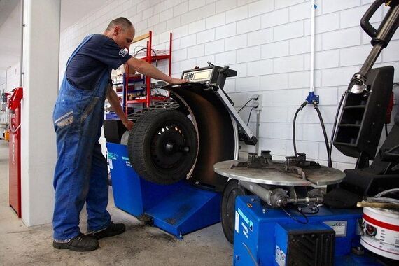 Monteur gebruikt bandenmontagemachine tijdens wielservice Monteur gebruikt bandenmontagemachine tijdens wielservice